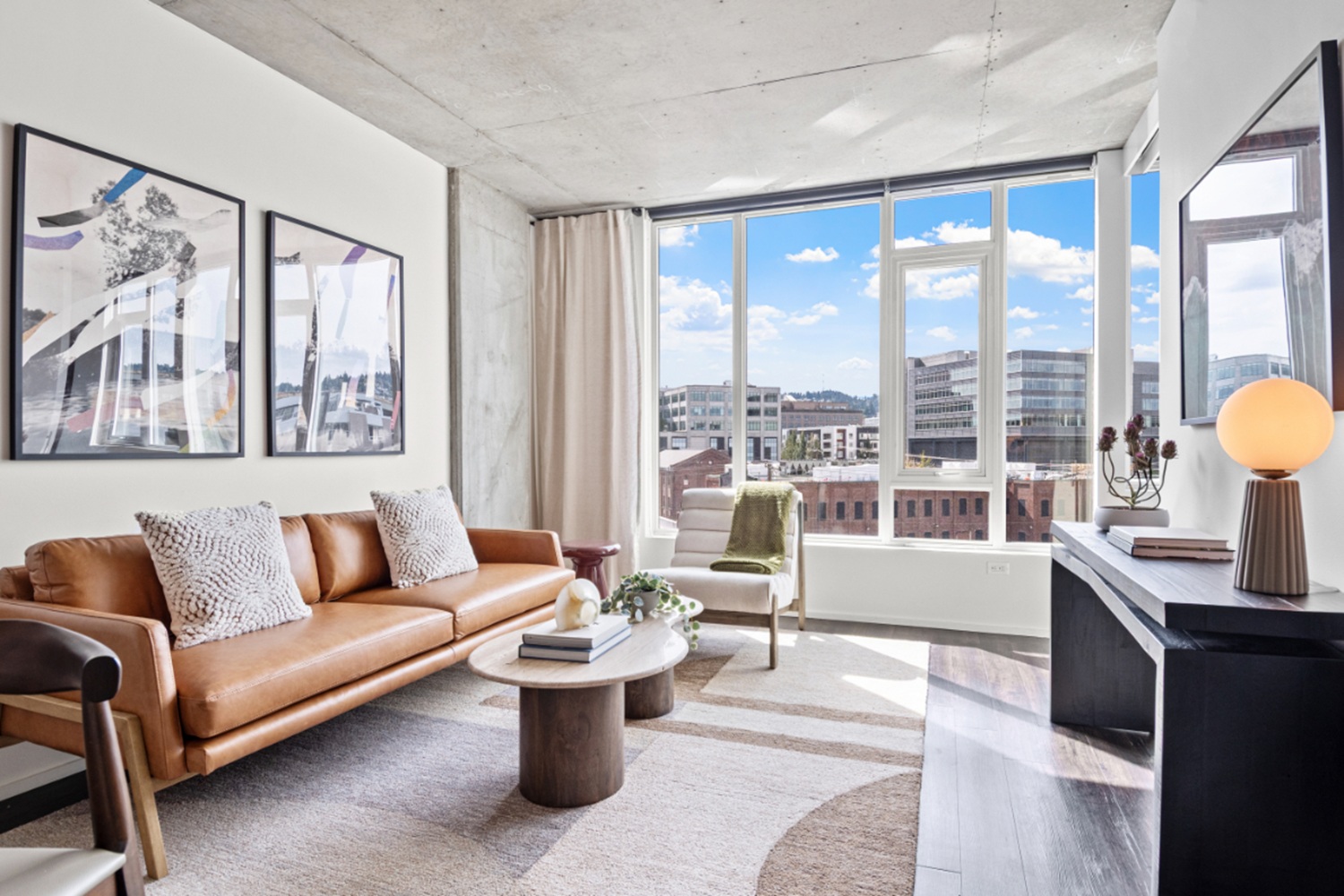 Apartment living room at NV Apartments with oversized windows, modern furniture, and Portland skyline views.
