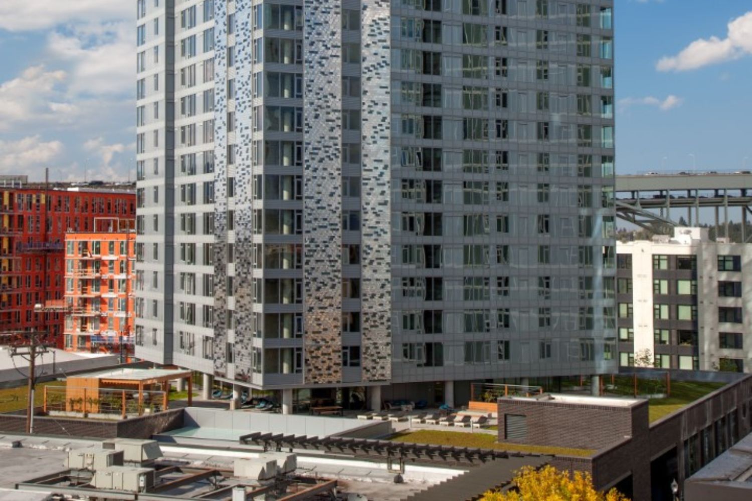 Exterior view of NV Apartments high-rise tower in Portland’s Pearl District under a bright blue sky.