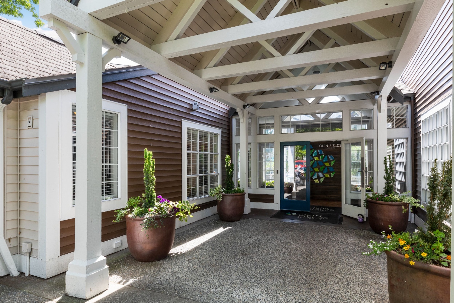 Entrance to Olin Fields Apartments featuring a covered walkway and potted plants.