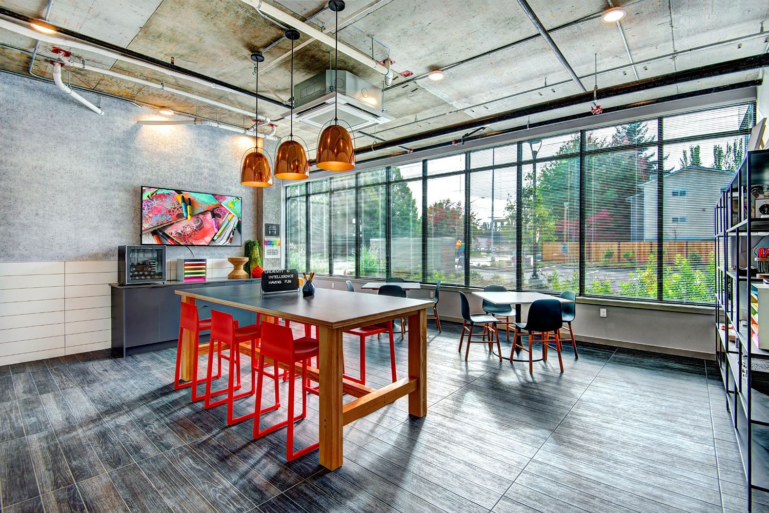 Art studio with communal tables, stools, and colorful supplies.