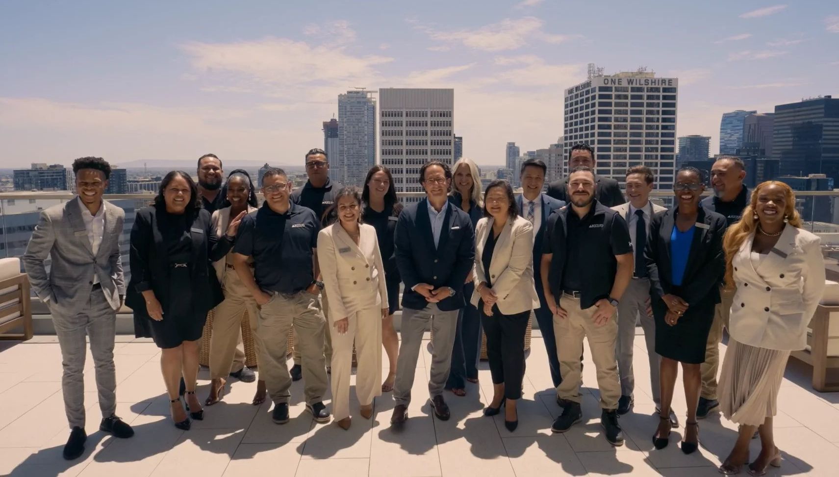 Group photo of diverse professionals on a rooftop with city skyline in background.
