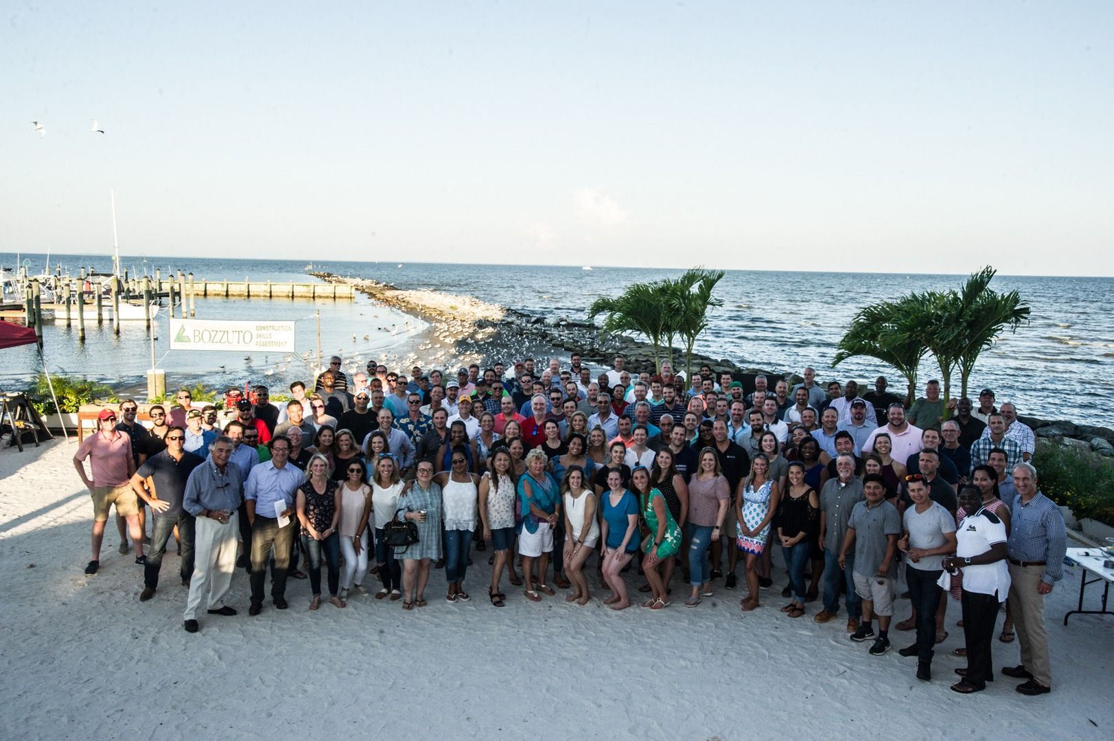 A large group of people posing together by the seaside.