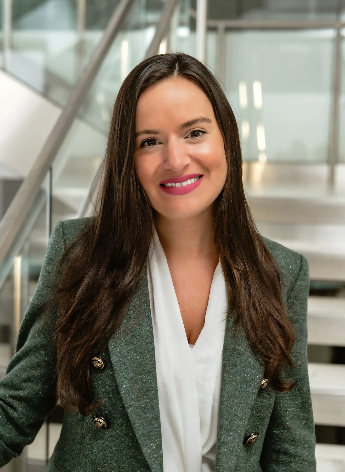Alyssa Boyle smiles in a modern indoor setting with a staircase behind her.