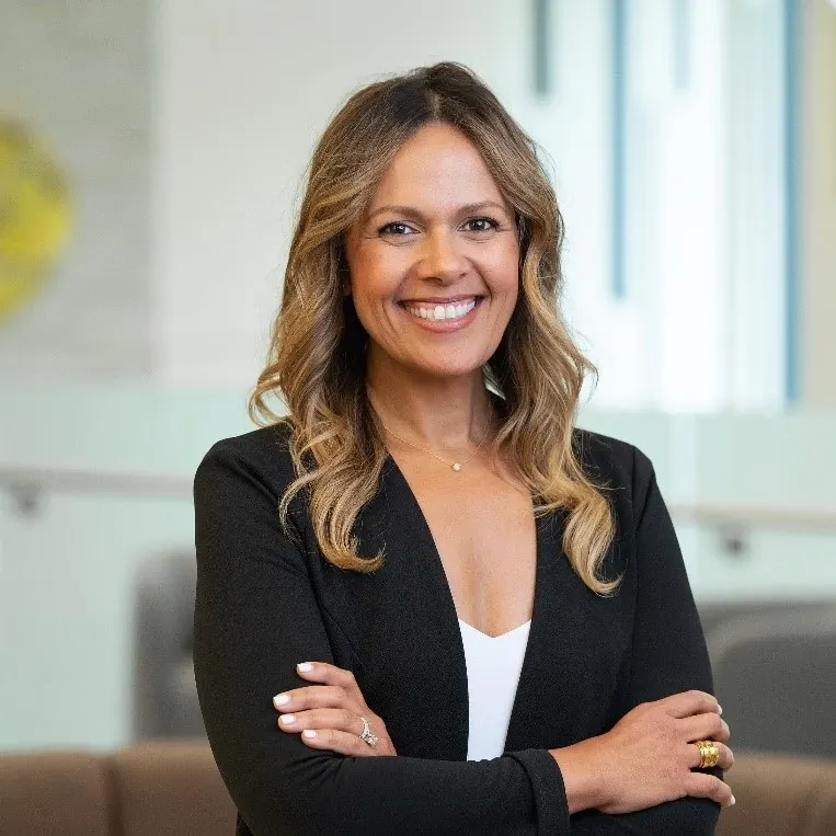 Smiling woman in a black blazer poses confidently, representing Adanise Cross.
