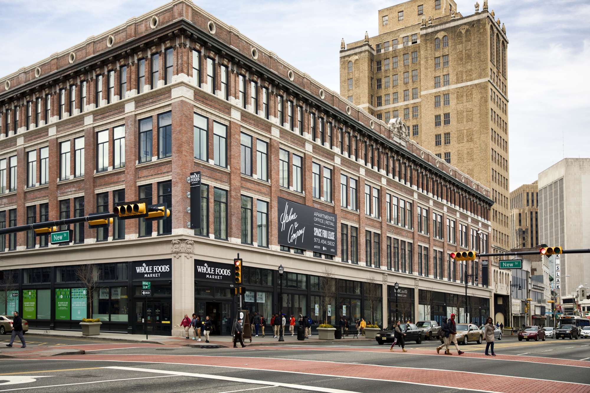 Historic brick building at an urban intersection with shops and pedestrians.