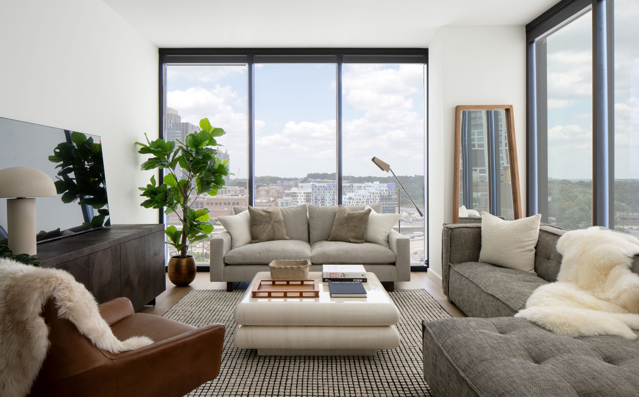 Modern living room with large windows, couch, and green plant.