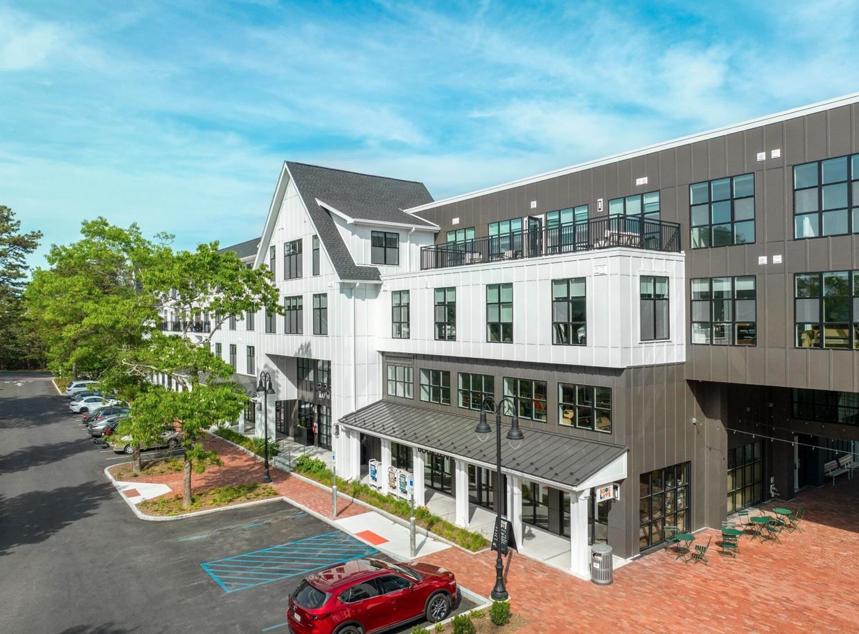 Modern multi-story building with large windows and greenery in front.