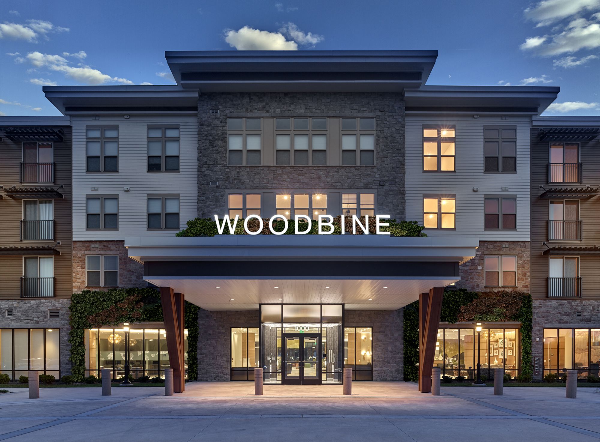 Modern building entrance with "WOODBINE" signage at dusk.